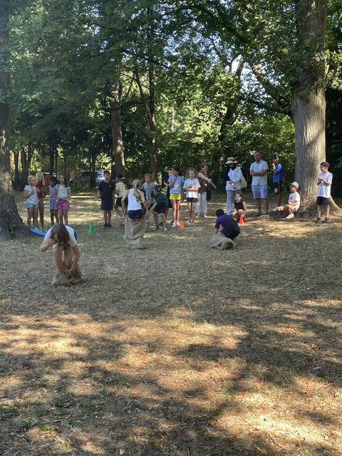 Kinder beim Sackhüpfen auf der Wiese im Seehofpark beim Ferragosto-Fest der Mühlbergschule