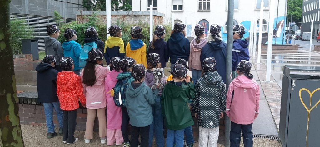 Die Klasse 1d von hinten mit schwarzen Piratentüchern am Mainufer beim Ausflug zu den Hafenpiraten in Frankfurt