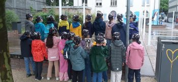 Die Klasse 1d von hinten mit schwarzen Piratentüchern am Mainufer beim Ausflug zu den Hafenpiraten in Frankfurt