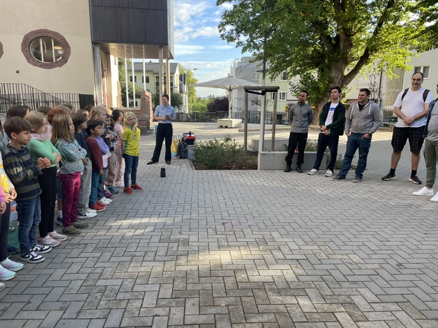 Schulkinder der Mühlbergschule stehen im Schulhof aufgereiht und begrüßen das Team von BNP Paribas beim Malteser Social Day