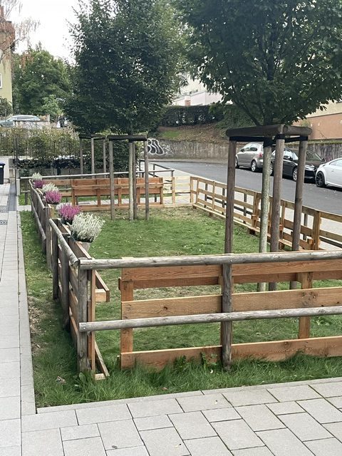 Fertige Holzumzäunung des künftigen Klassenzimmers im Freien, geschmückt mit Blumen, auf der Grünfläche an der Mühlbergschule