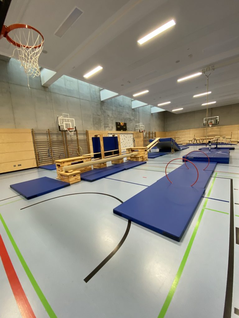 Lange blaue Matte mit roten Reifen in der Turnhalle, Station des Be Active Day Parcours