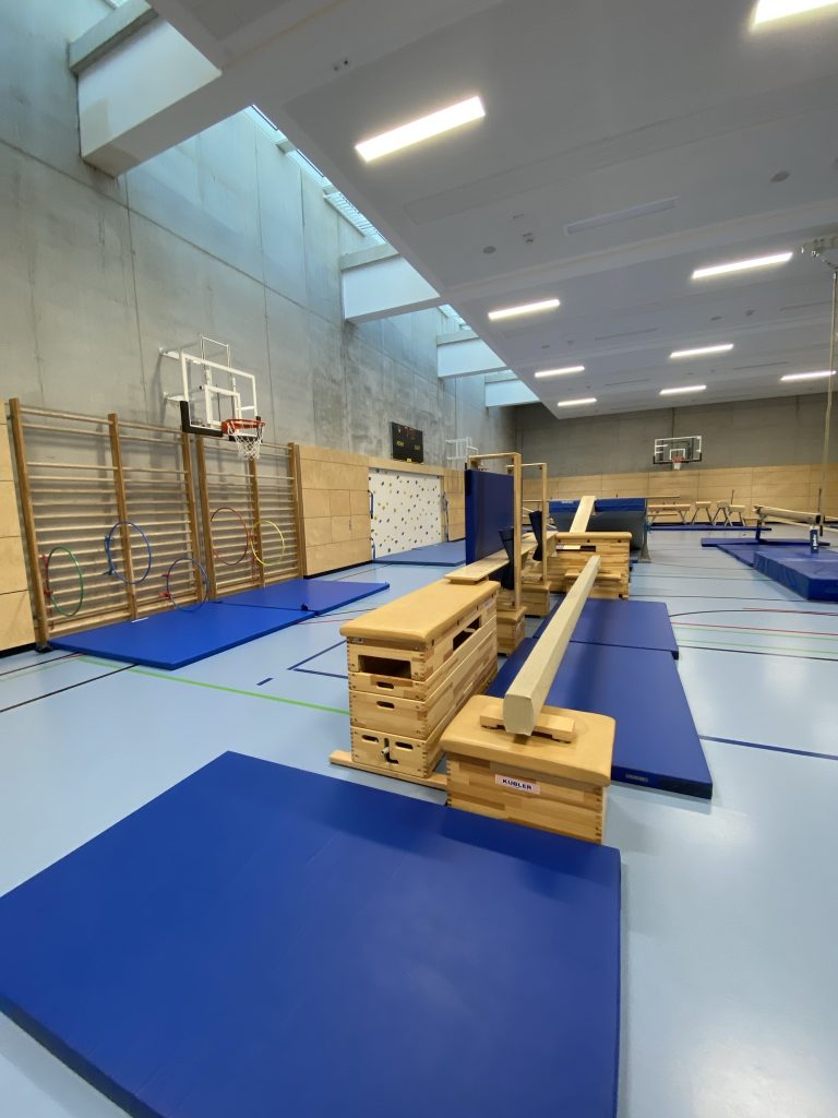Schräg angelegte Bank an einem Holzkasten mit Matte davor, Station im Be Active Day Parcours