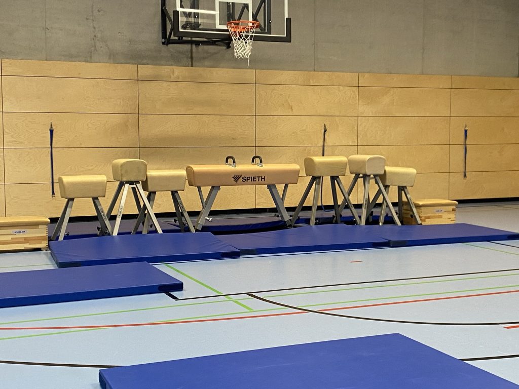Sprungbock und Pauschenpferde vor der Hallenwand mit Matten, Be Active Day Parcours