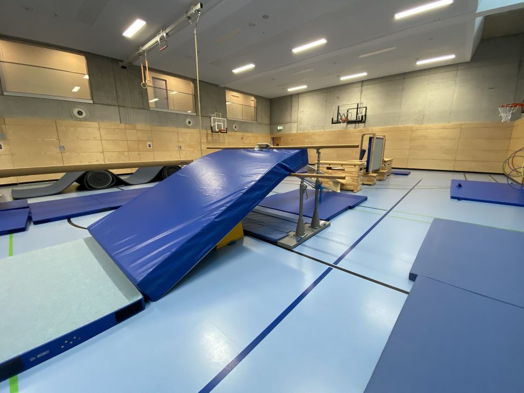 Schräg aufgestellte blaue Matte als Rampe vor weiteren Geräten, Parcours des Be Active Day