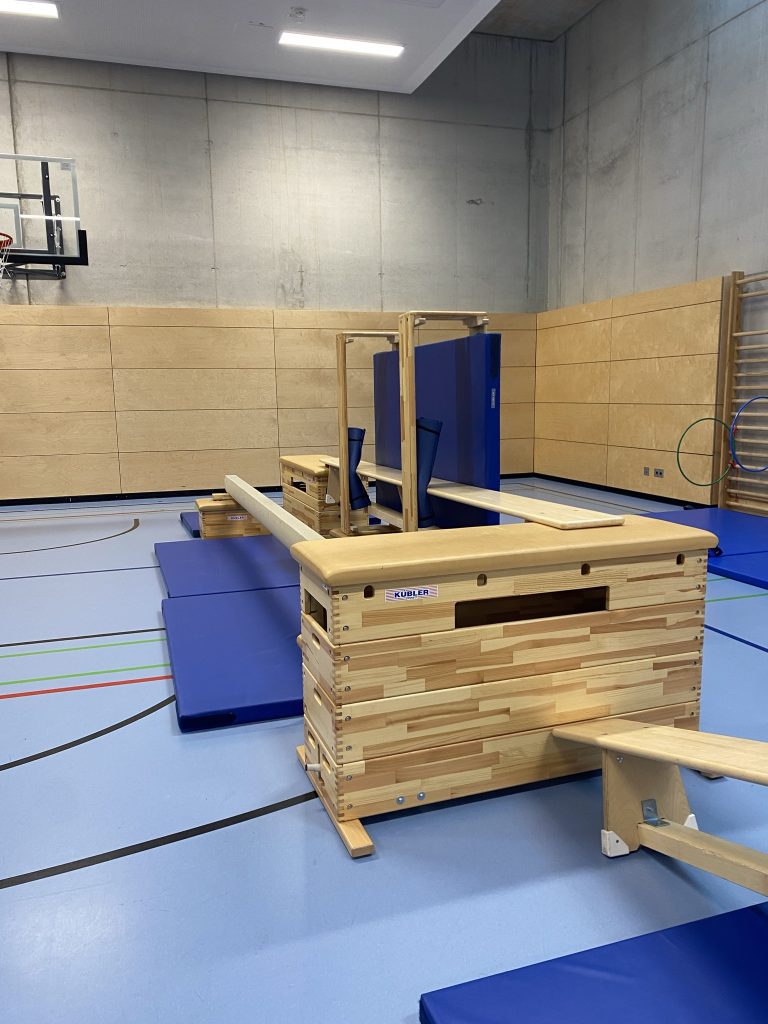 Großer Holzkasten mit angelegten Bänken und Matten in der Turnhalle, Be Active Day Parcours