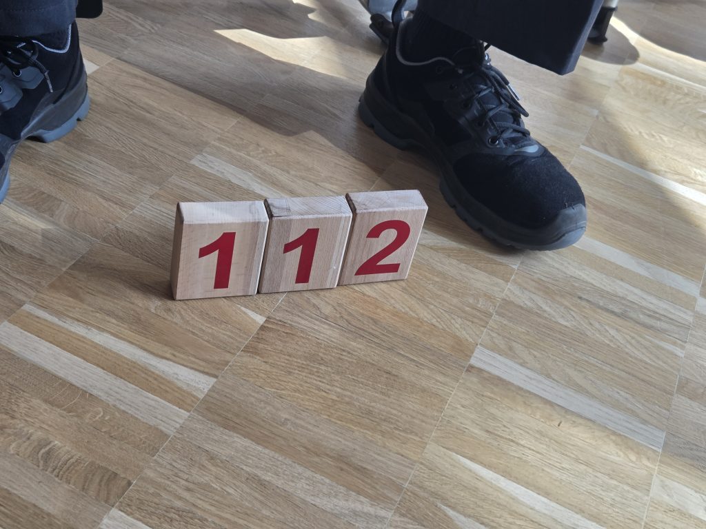 Holzwürfel mit der Notrufnummer 112 auf dem Boden, Brandschutzerziehung der Feuerwehr Jahrgang 4