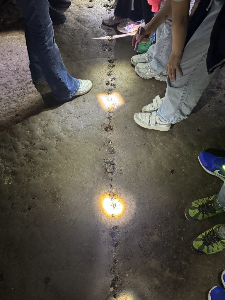 Kinderfüße und Taschenlampenlicht auf dem Boden der Fischerhallen bei der Erkundung unter der Brücke