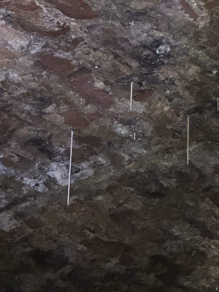 Raue, dunkle Steinwand mit weißen Markierungen im Gewölbe der Fischerhallen unter der Alten Brücke